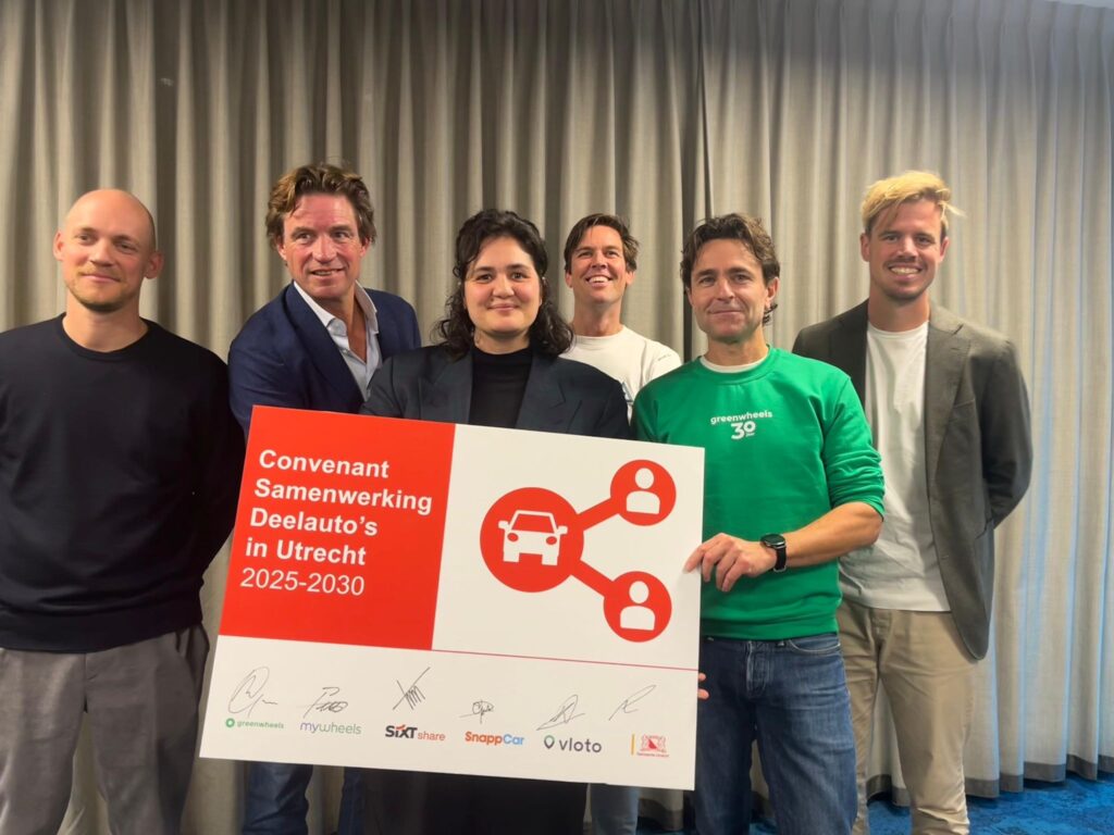 Vertegenwoordigers van deelautobedrijven houden een bord met de tekst ‘Convenant Samenwerking Deelauto’s in Utrecht 2025–2030’ vast