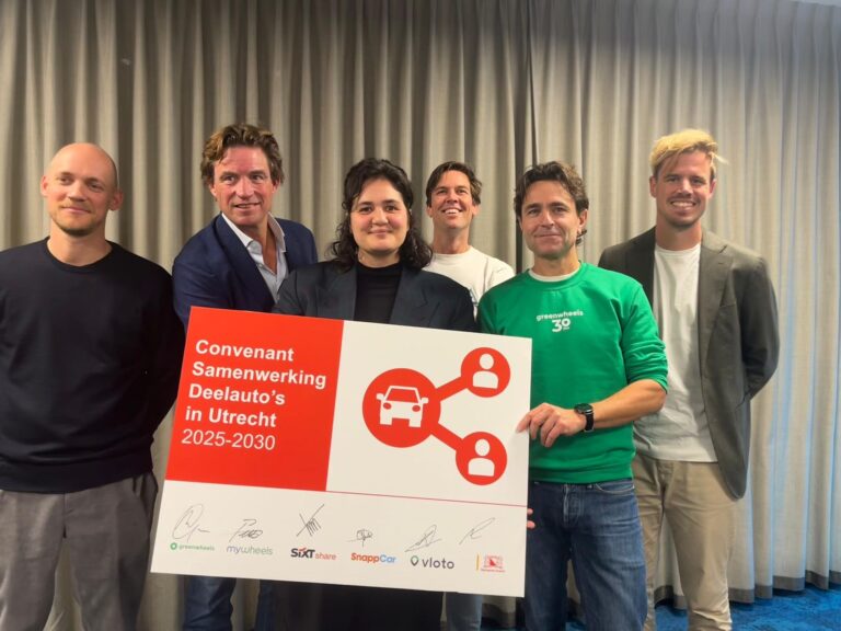 Vertegenwoordigers van deelautobedrijven houden een bord met de tekst ‘Convenant Samenwerking Deelauto’s in Utrecht 2025–2030’ vast