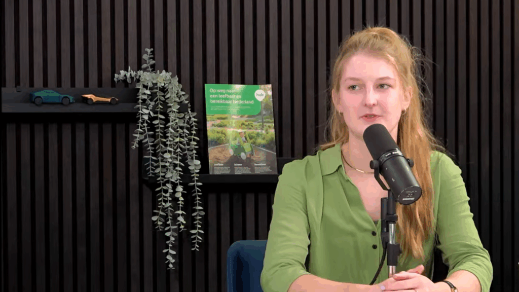 Spreker in N!D Liveshow; studiosetting met microfoon, op de achtergrond het magazine ‘Op weg naar een leefbaar en bereikbaar Nederland’.