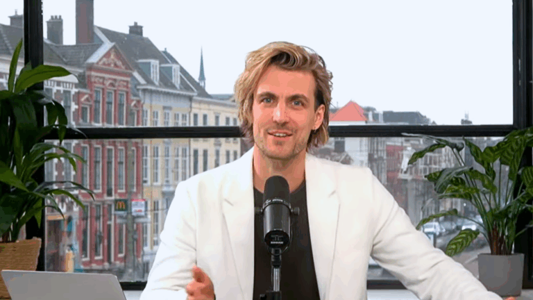 Still uit N!D Liveshow Modelbepalingen & Flexibele Parkeermachtiging: host in studio met microfoon; stadsgezicht op achtergrond